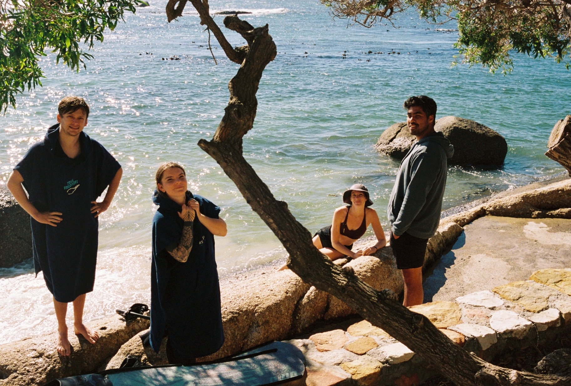Crew drying off in ponchos at a rocky cove