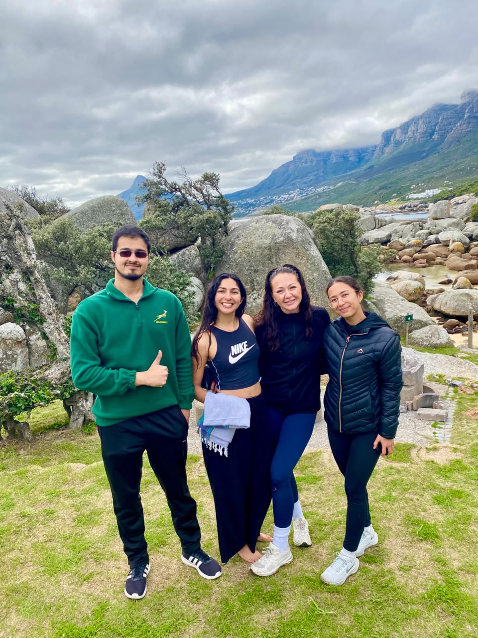 Four volunteers together on the grass with the mountains behind