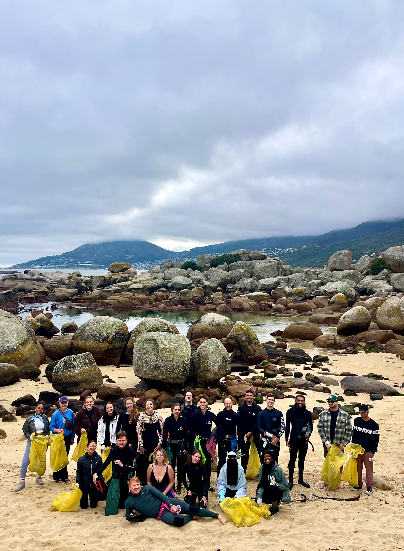 Large cleanup crew with yellow bags of collected trash on the beach