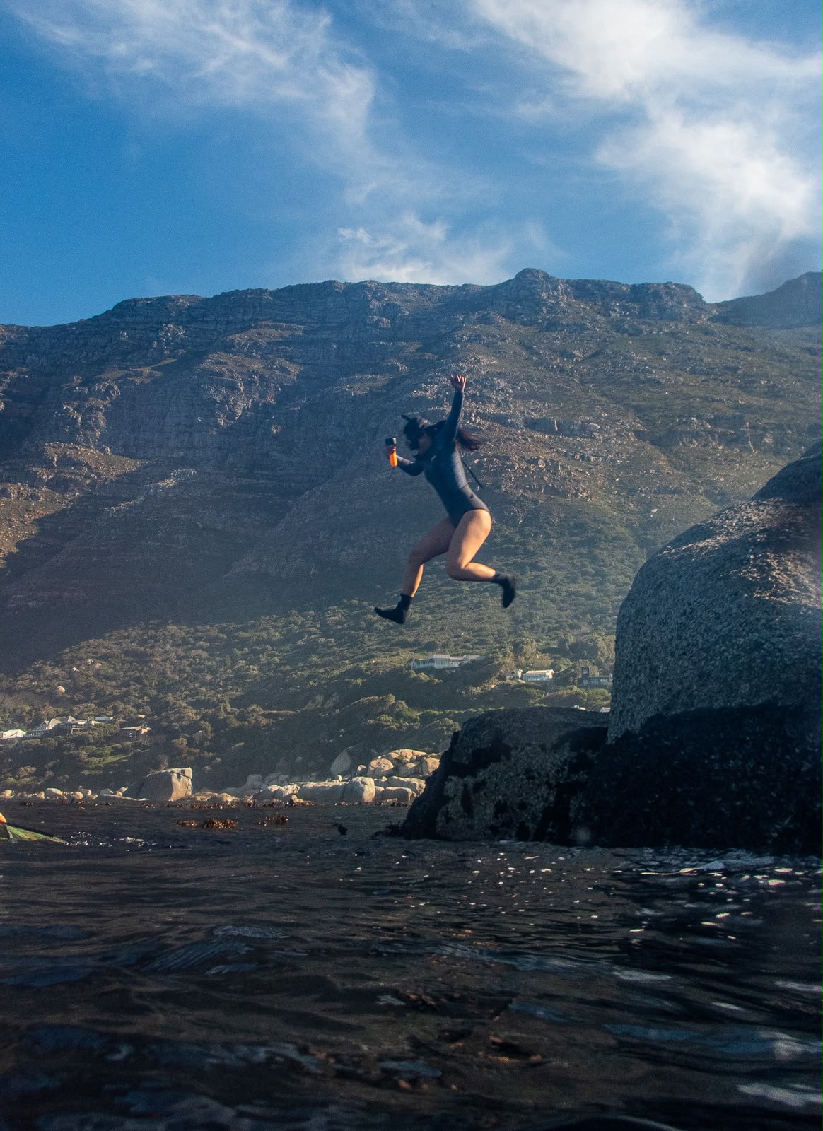 Swimmer leaping from the rocks into the ocean