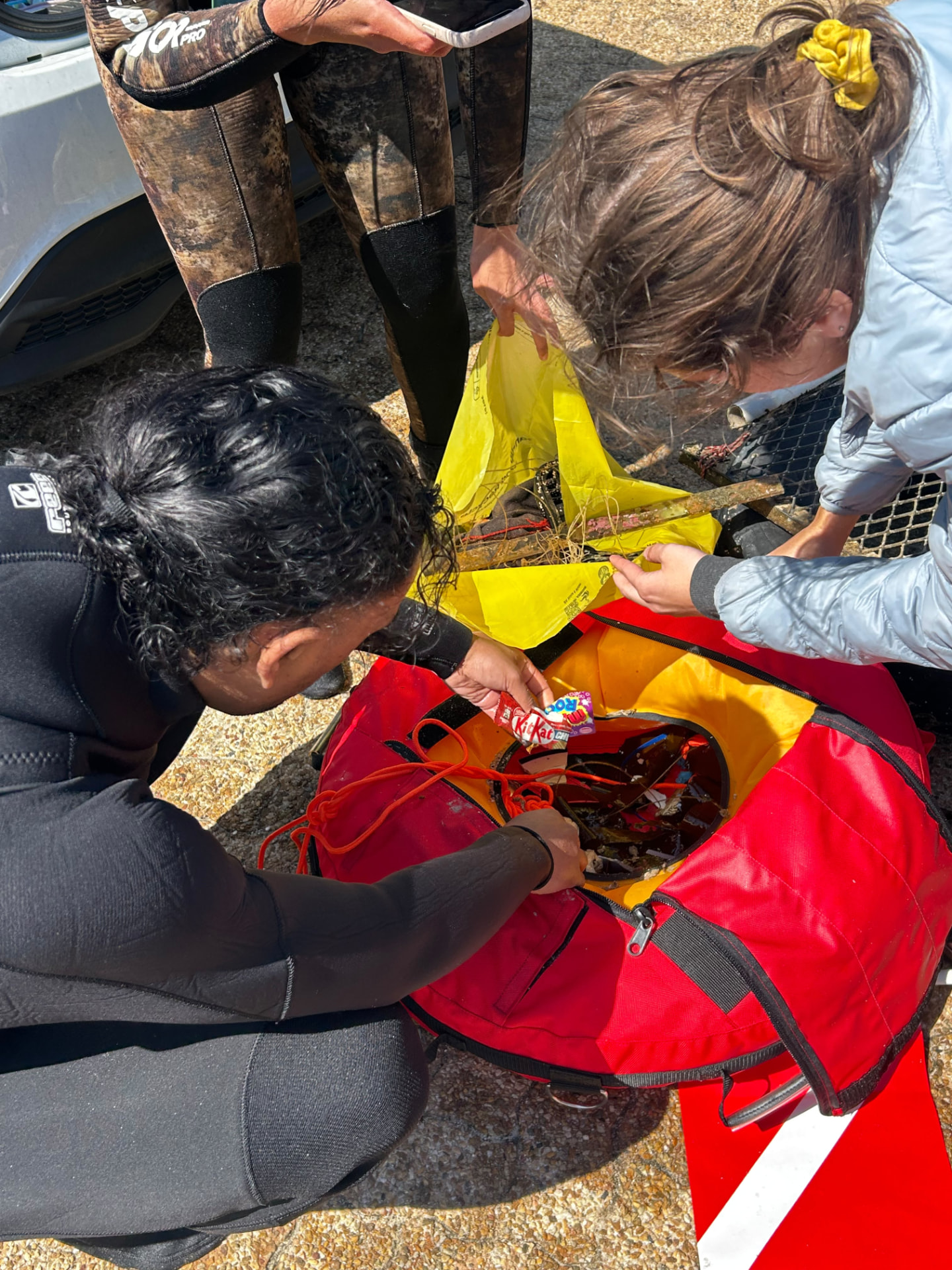 Volunteers sorting trash out of a dive bag after a cleanup